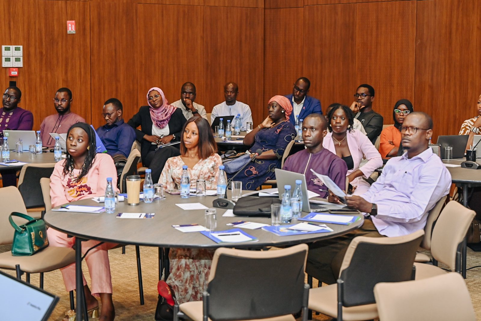 Participants assis autour de tables rondes suivant une présentation